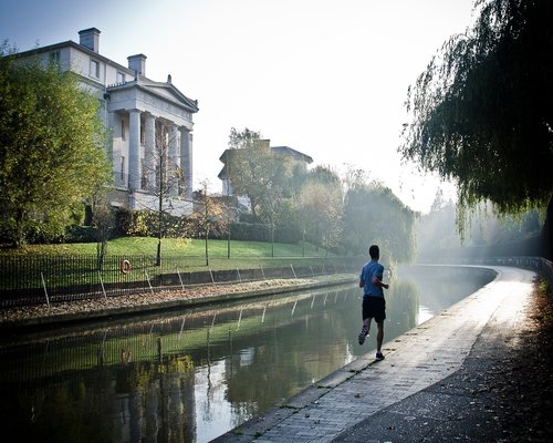 fit Indian man jogging in a green park during early morning